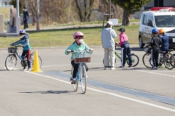 白い自転車に乗った小学生がコースを走っている様子の写真