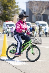 緑の自転車に乗ってコースを走っている女子小学生の写真