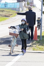 自転車を降りて手押ししている女子小学生の写真