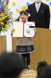 壇上で卒園証書を開いて披露している卒園児童の写真その4