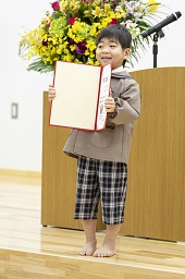 壇上で卒園証書を開いて披露している卒園児童の写真その1