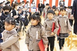 卒園証書を持ちながら会場を後にしている園児たちとそれを見守っている父母の写真