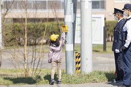 横断歩道の前の歩行者用ボタンを押している小学生の写真