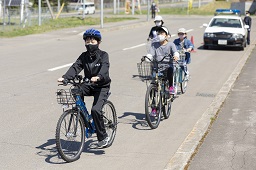 3人の小学生が一列になって自転車に乗っている写真
