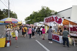 道路沿いに並んでいるバナナチョコや広島お好み焼きなどの屋台に集う人々の写真