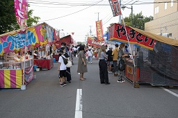 道路沿いに並んでいるクレープ屋さんややきとりなどの屋台に集う人々の写真