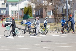 横断歩道で自転車を降りて手押ししている小学生たちの写真