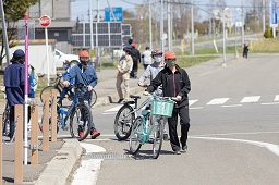 曲がり角で自転車を降りて手押ししている小学生たちの写真