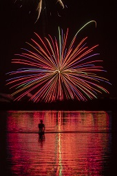 闇夜に赤い打ち上げ花火が咲いている様子の写真