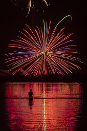 闇夜に赤い打ち上げ花火が咲いている様子の写真