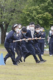 白いはちまきをした4人の中学生が横一列に並んで白い棒を持ってグラウンドを走っている写真その2