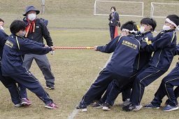 グラウンドで白いはちまきを着けた中学生たちが相手の中学生たちと綱引きをしている写真