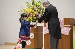 園長先生から卒園証書を受け取っている女児卒園児の写真