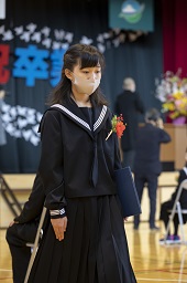 卒業証書を手に自分の席に戻ろうとしている女子卒業生の写真