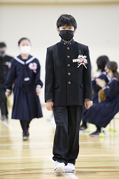 体育館に入場してくる制服姿の新一年生の男子の写真