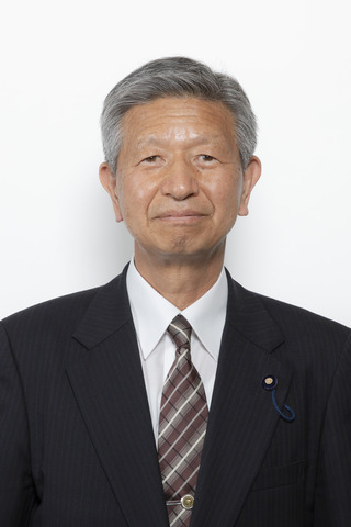 黒いスーツにチェックのネクタイをしめた鈴木秀之さんが正面を向いている写真