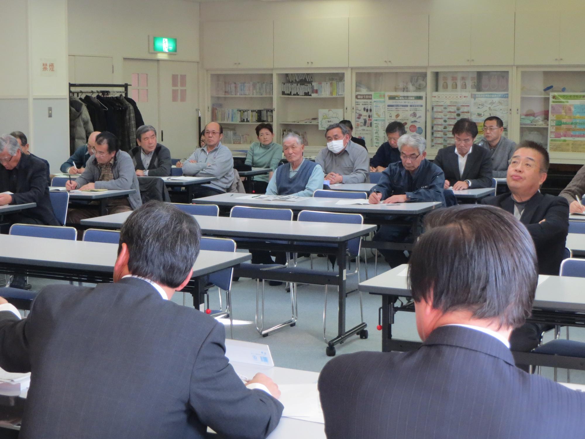 椅子と机の並んだ会議室で会議に参加する複数名の町民の写真