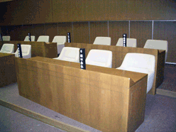 白い椅子が3つずつ設置された複数の長机にそれぞれ黒い氏名標が立てられている様子の写真