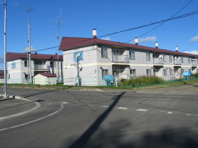 白くて四角い煙突のある赤い屋根の二階建て住宅の写真