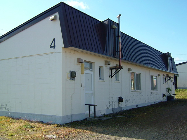 白い壁の側面に4と番号が書かれたへの字型の屋根が特徴の長屋住宅の写真