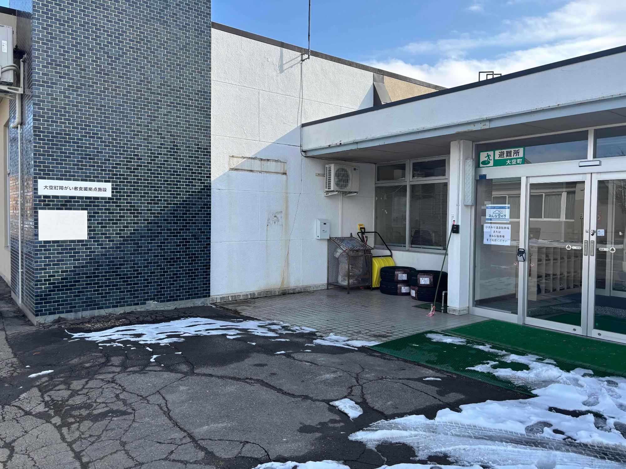 黒いタイル張りの外壁に看板が貼られている障がい者支援拠点施設の写真