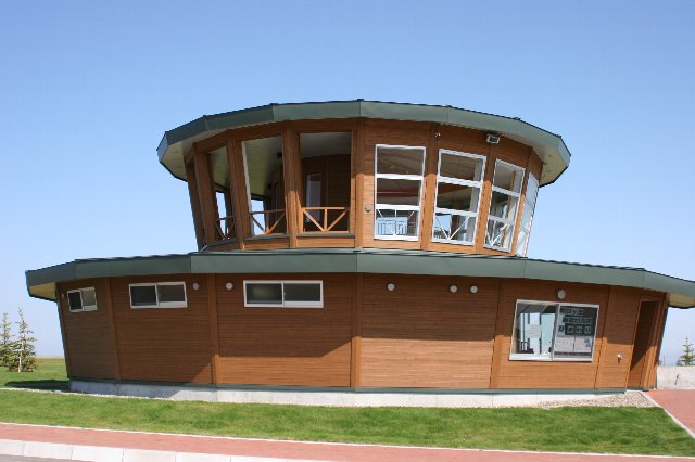 屋外に設置された2階建ての茶色の円柱型の建物の写真