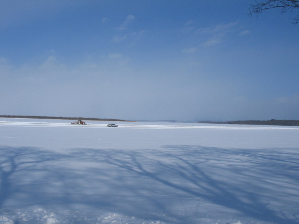 透き通るような青空の下、地平線の彼方まで真っ白に雪が積もった網走湖の写真