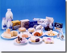 青い壁をバックに瓶の牛乳や箱入りのチーズ、小皿に載った複数の菓子が並べられた写真