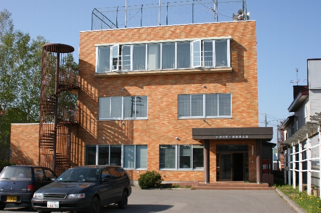レンガ色のタイルに覆われた3階建ての女満別地域振興会館の写真